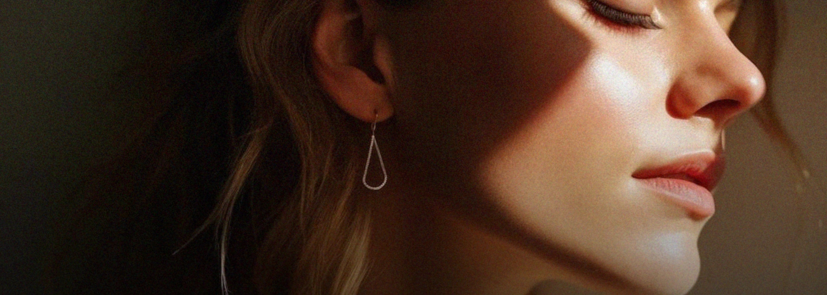 Close-up of a woman wearing a silver earring with a dark background
