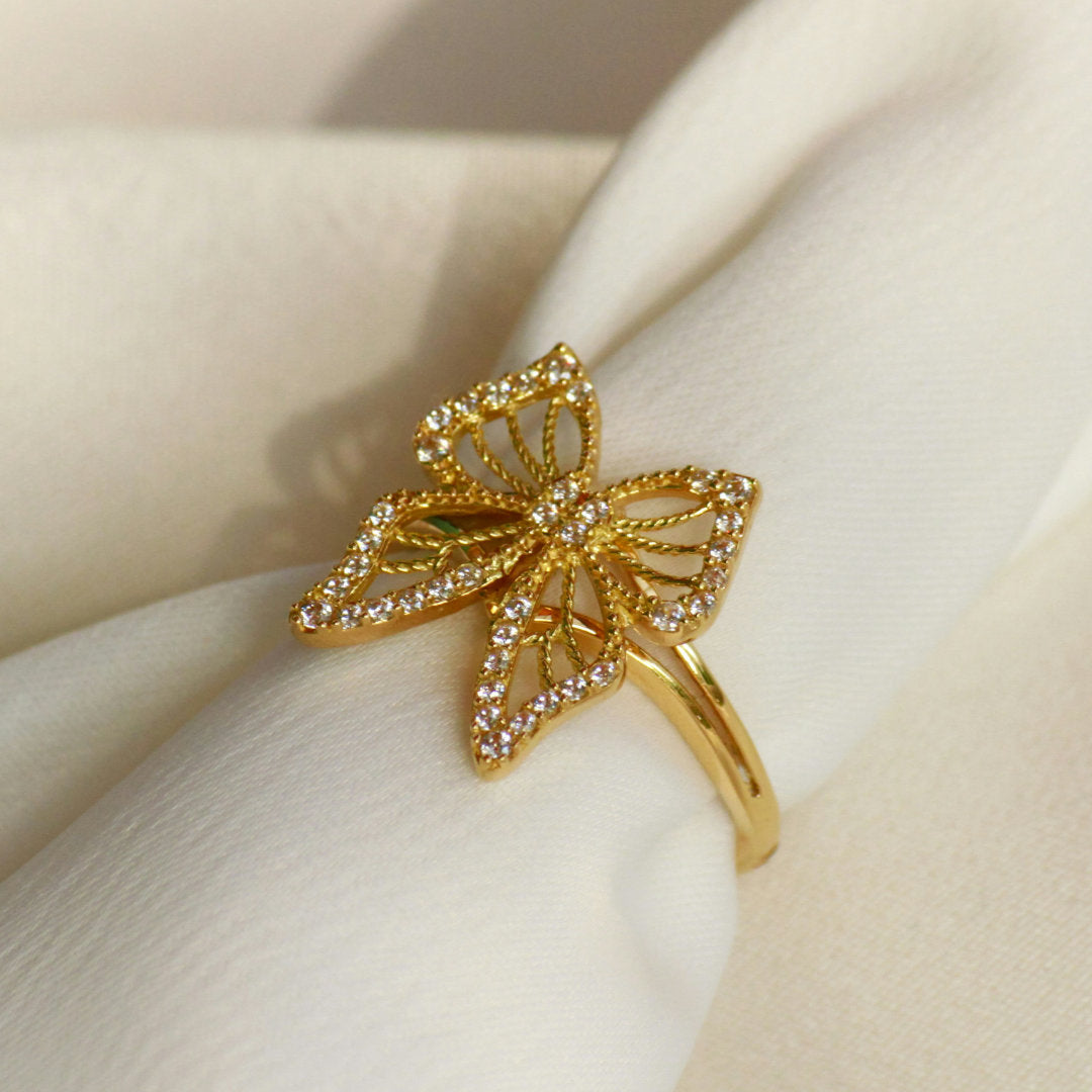 Gold butterfly ring with gemstones on a beige fabric background