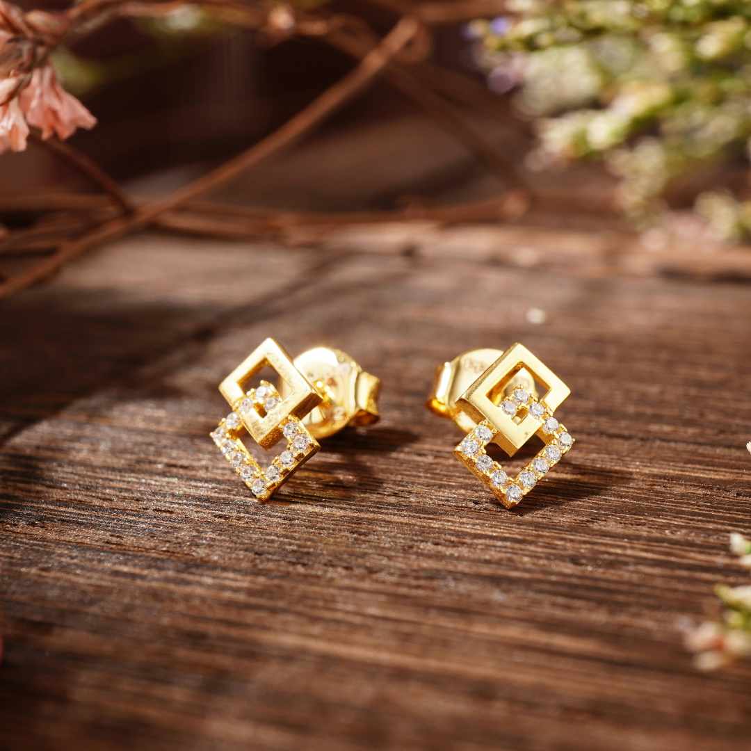 Gold earrings with diamond accents on a wooden surface