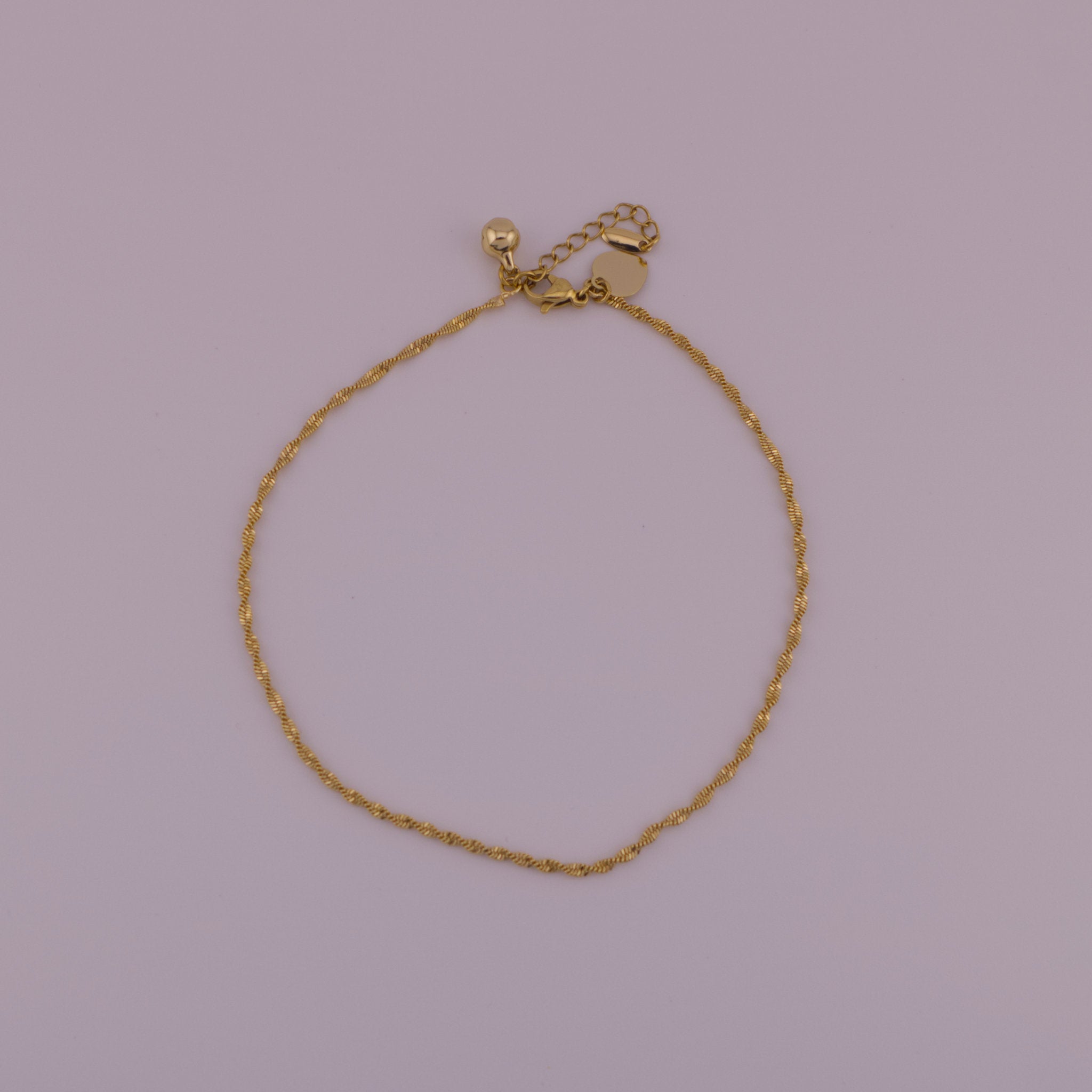 Gold bracelet on a light purple background