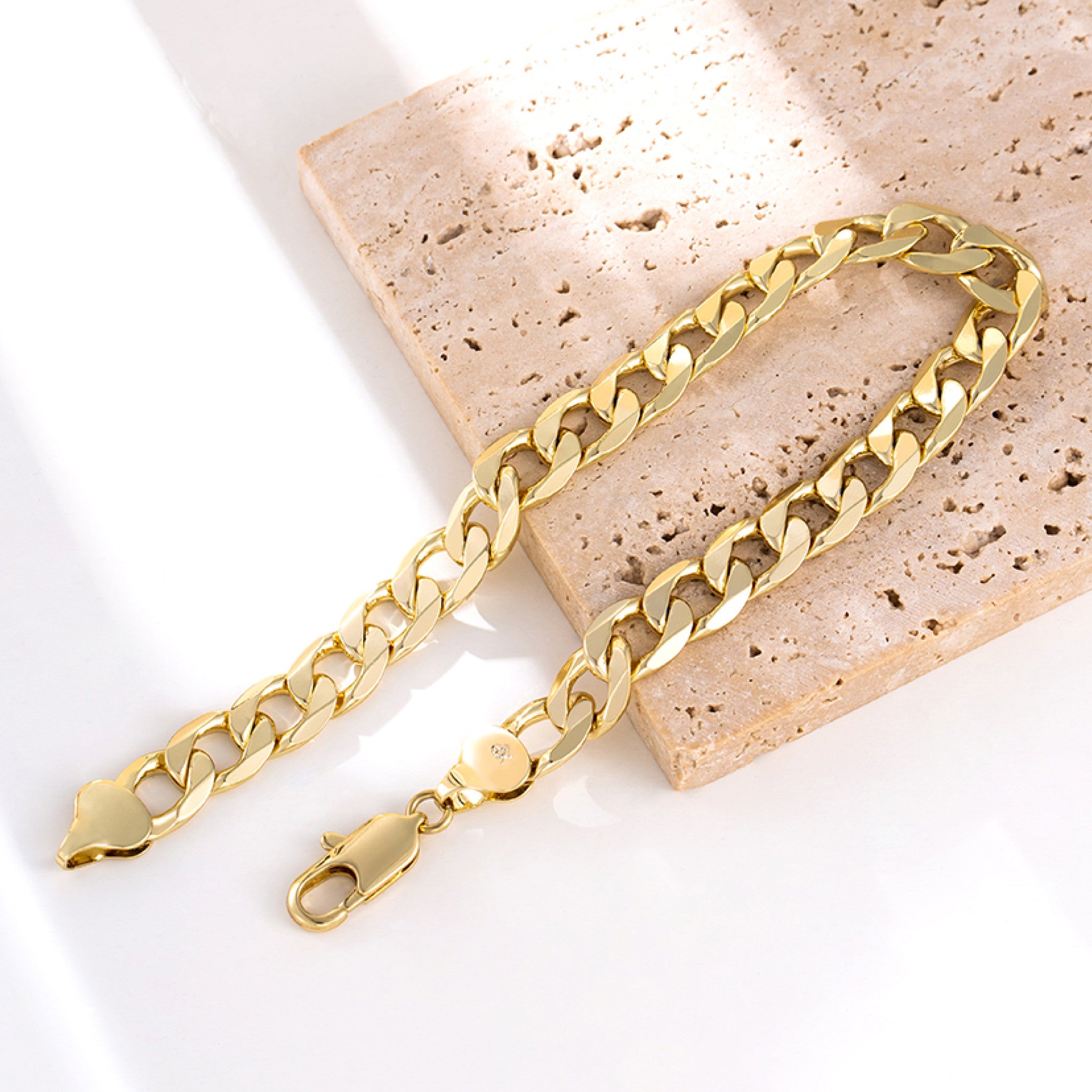 Gold chain anklets on a textured stone surface
