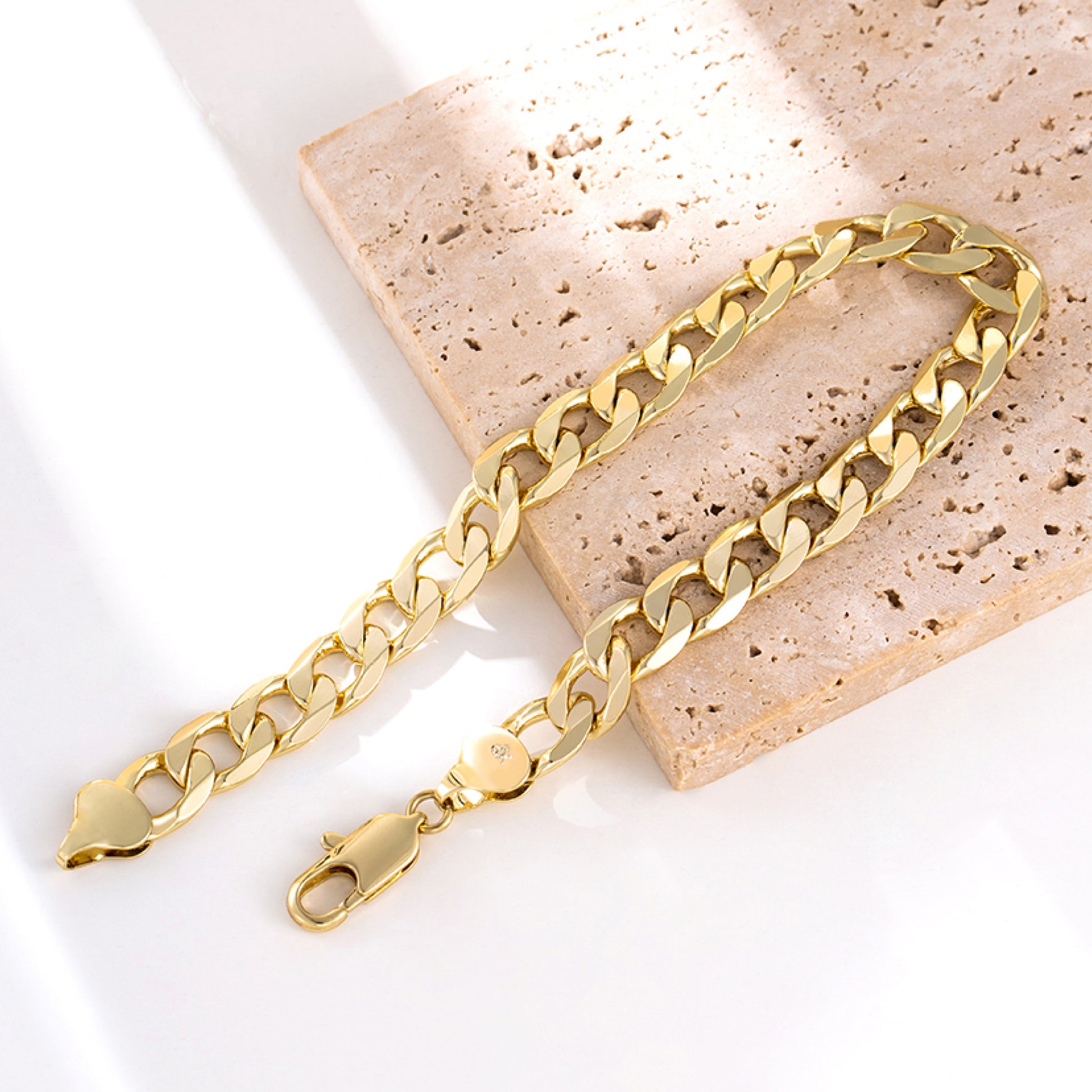 Gold chain anklets on a textured stone surface