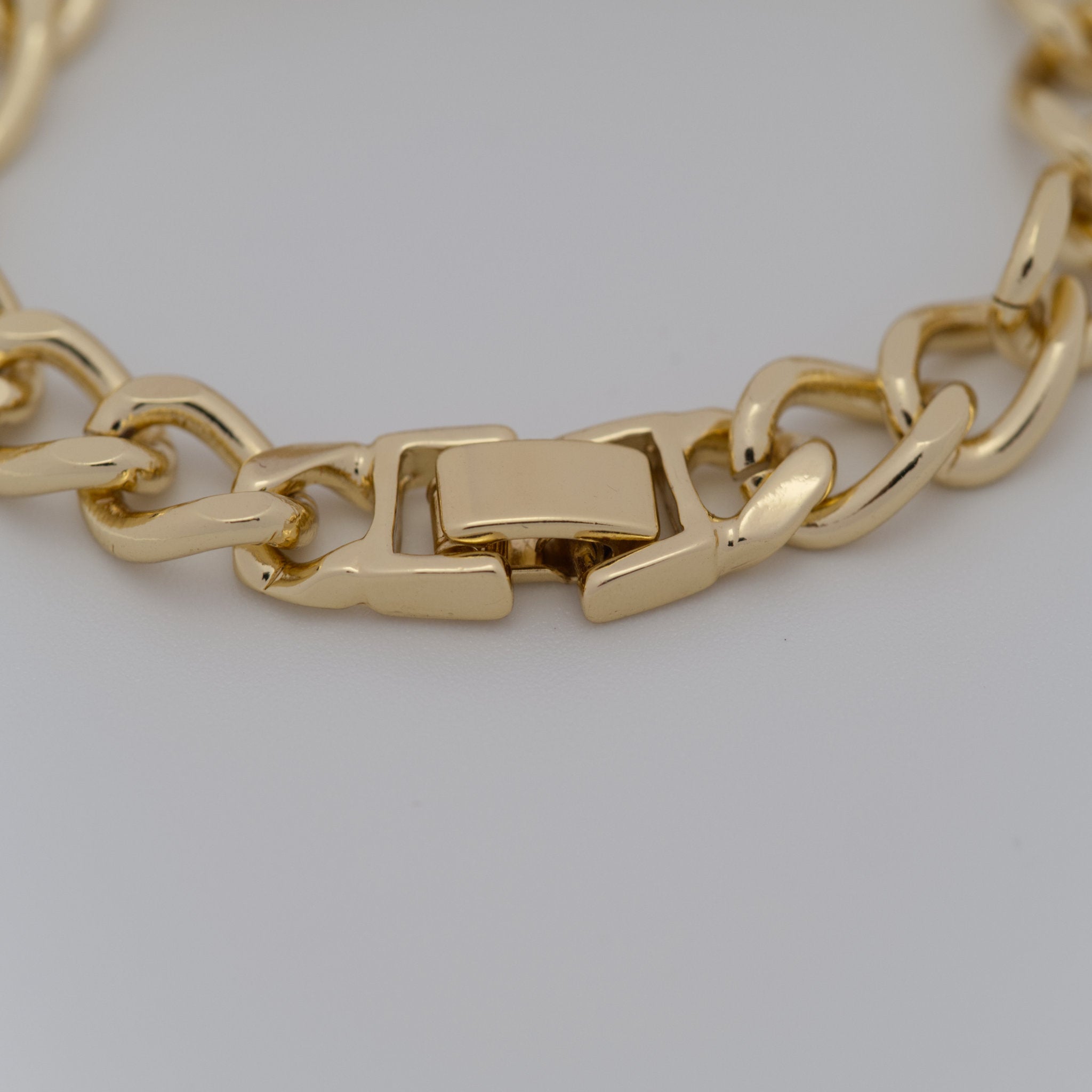 Gold chain bracelet on a light gray background