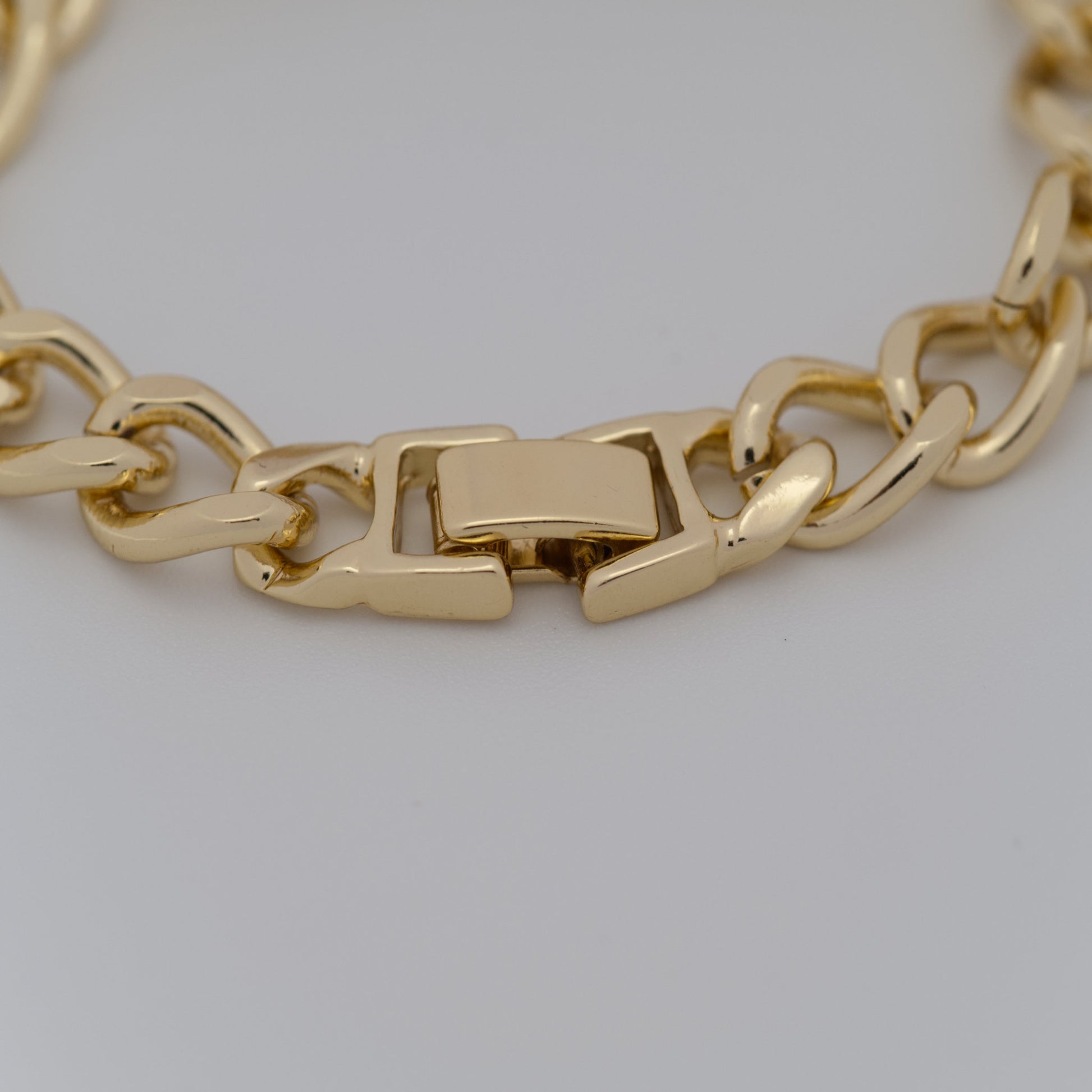 Gold chain bracelet on a light gray background