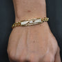Gold bracelet with diamond accents on a wrist against a dark background