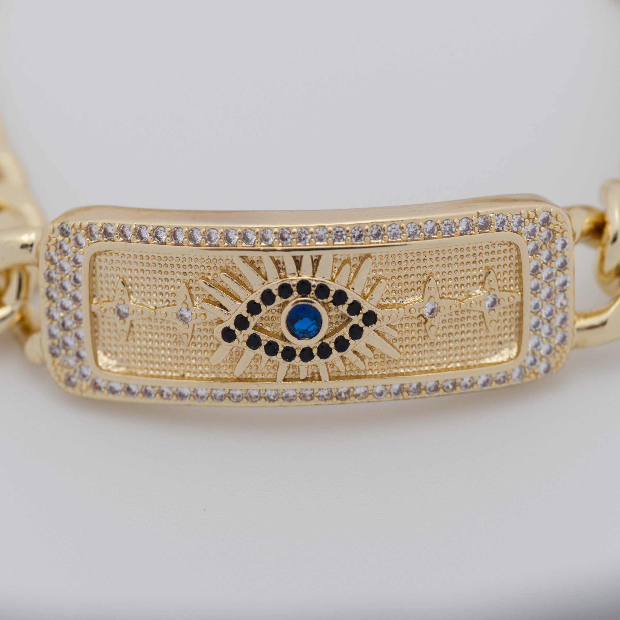 Gold bracelet with eye design and blue gemstone on a white background