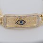 Gold bracelet with eye design and blue gemstone on a white background