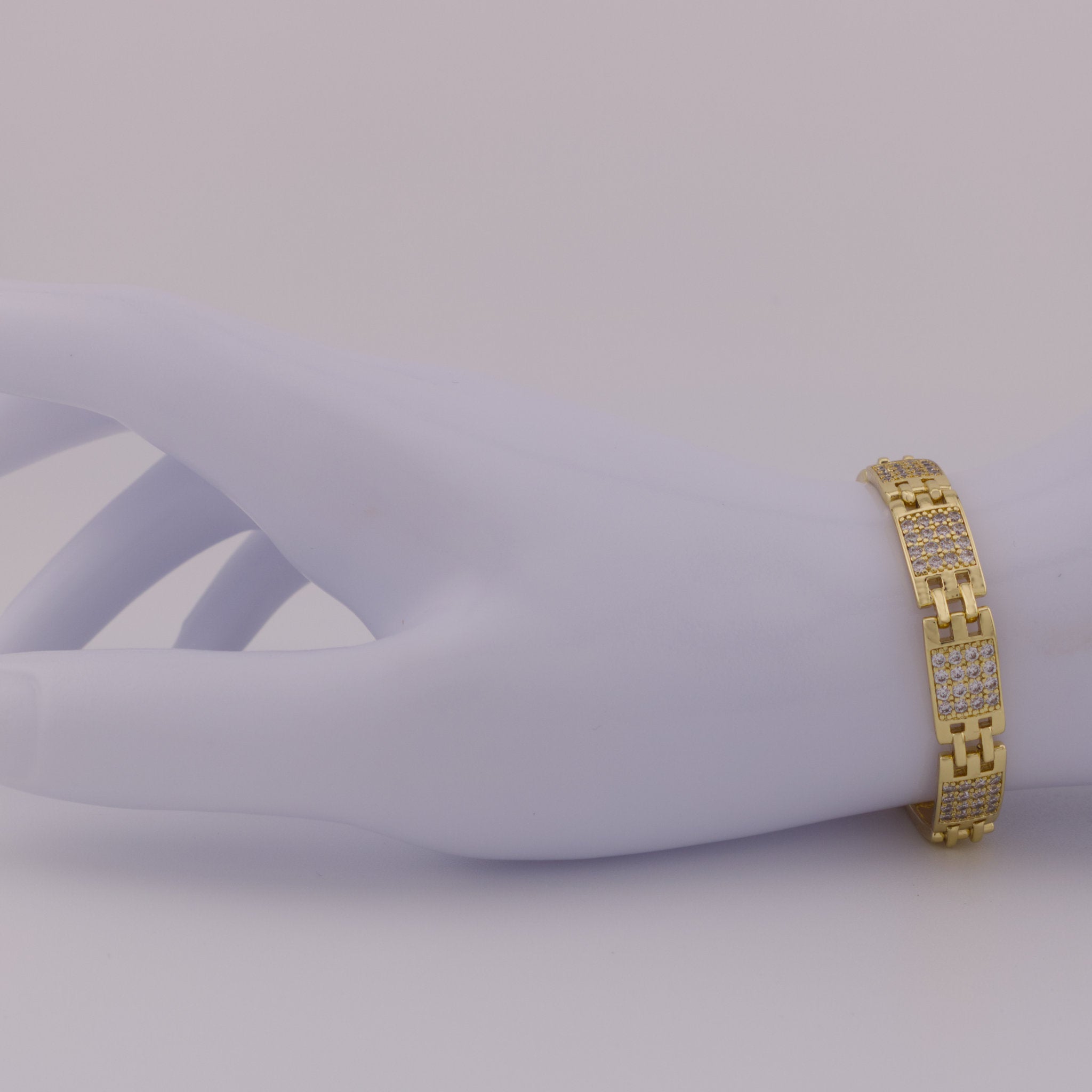Gold bracelet on a mannequin arm against a plain background