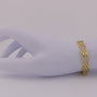 Gold bracelet on a mannequin arm against a plain background