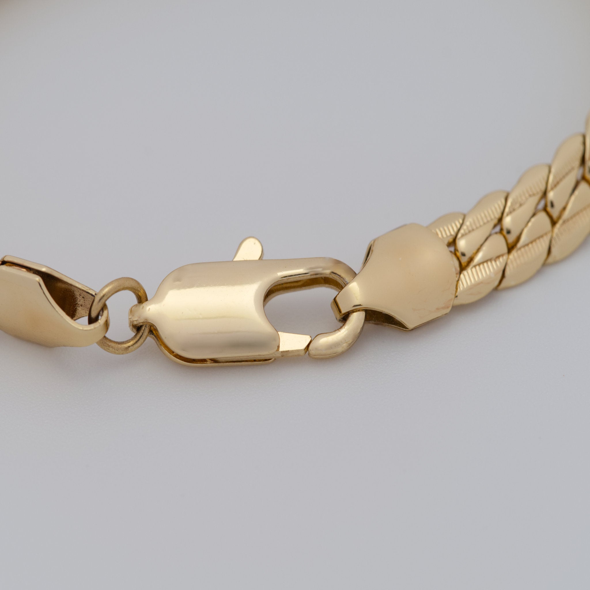 Gold chain bracelet on a light gray background