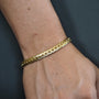 Gold bracelet on a wrist against a dark background