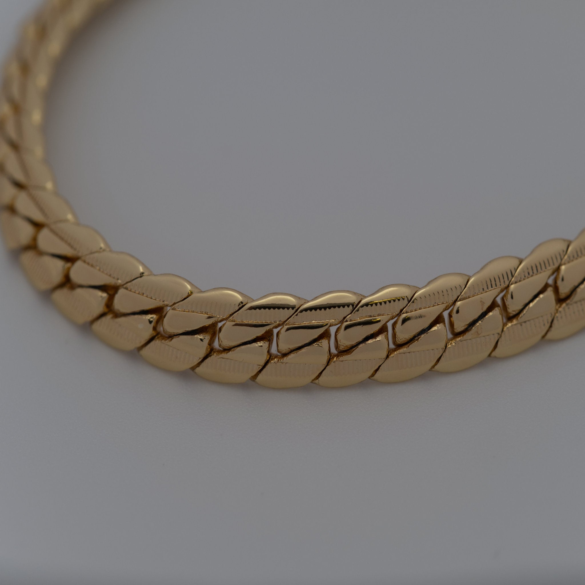 Gold braided necklace on a light gray background