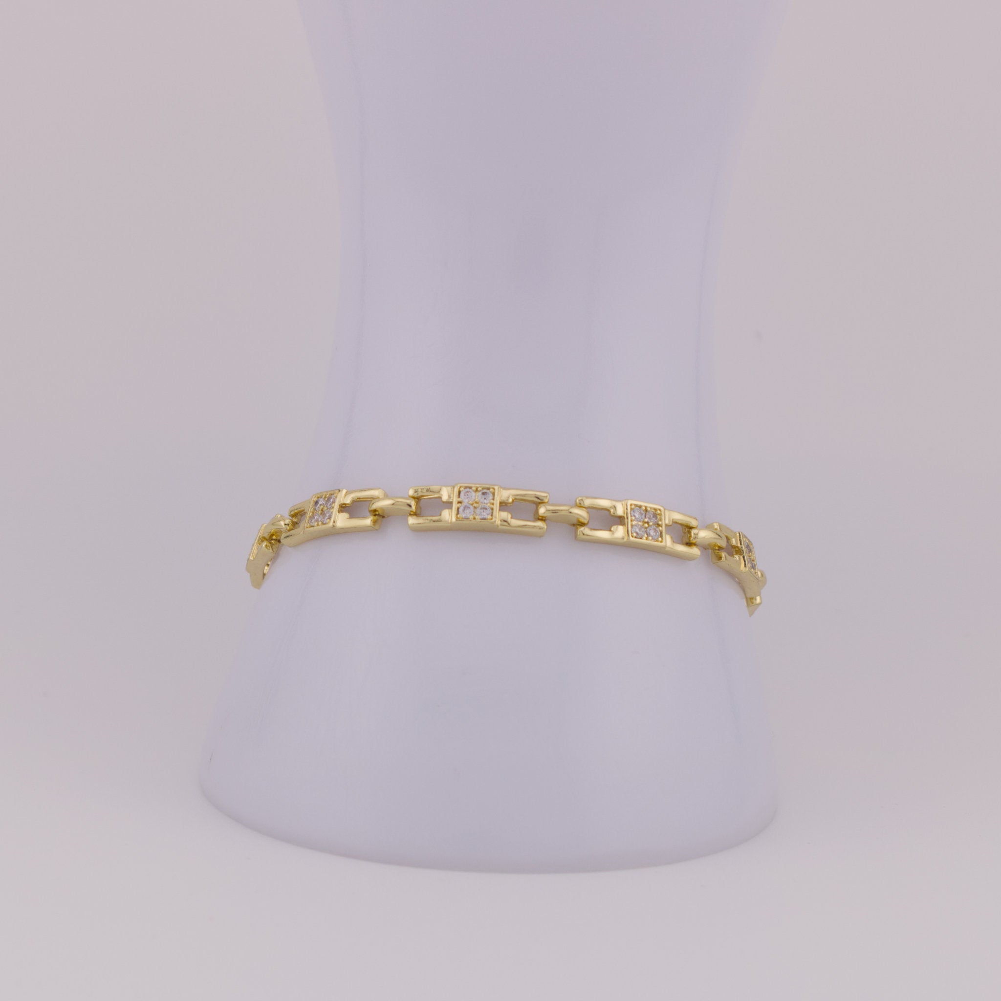 Gold bracelet with diamond accents on a light gray background