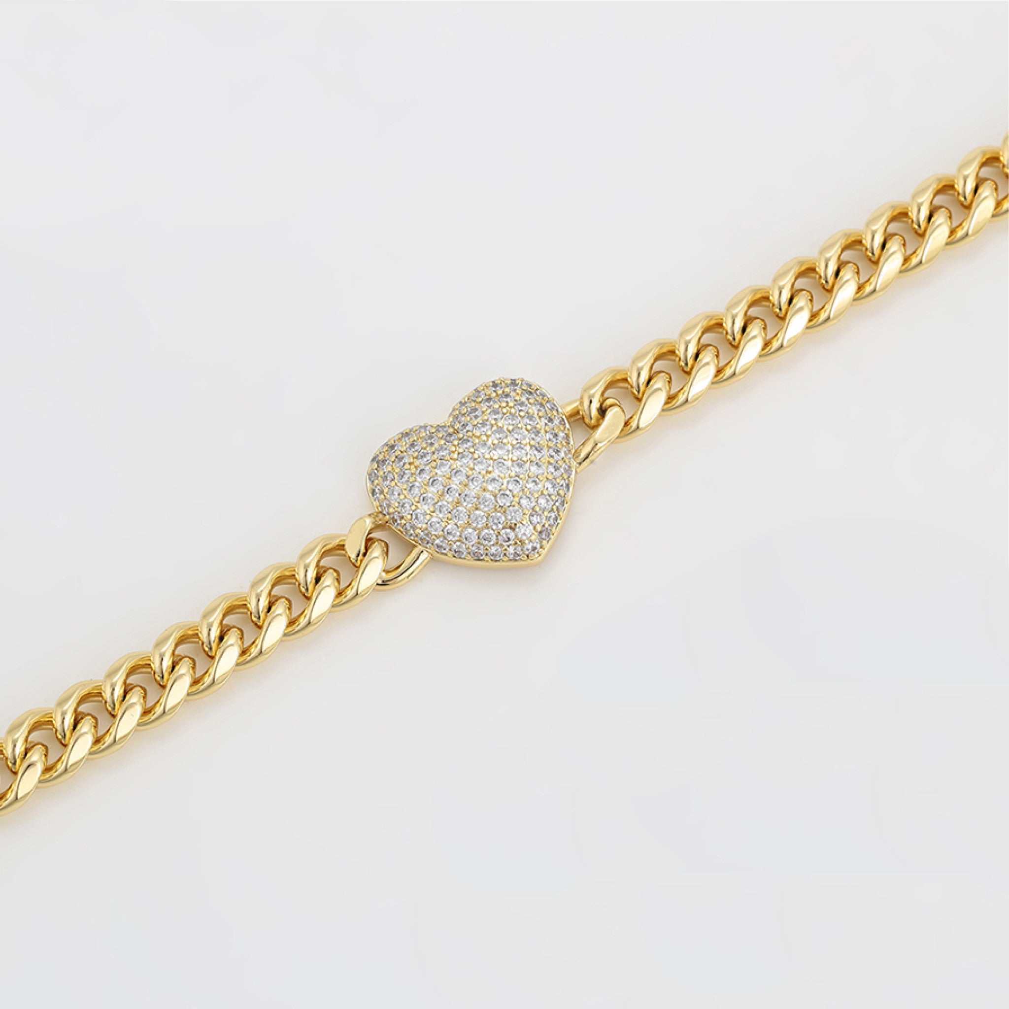 Gold chain bracelet with a heart-shaped diamond clasp on a light gray background
