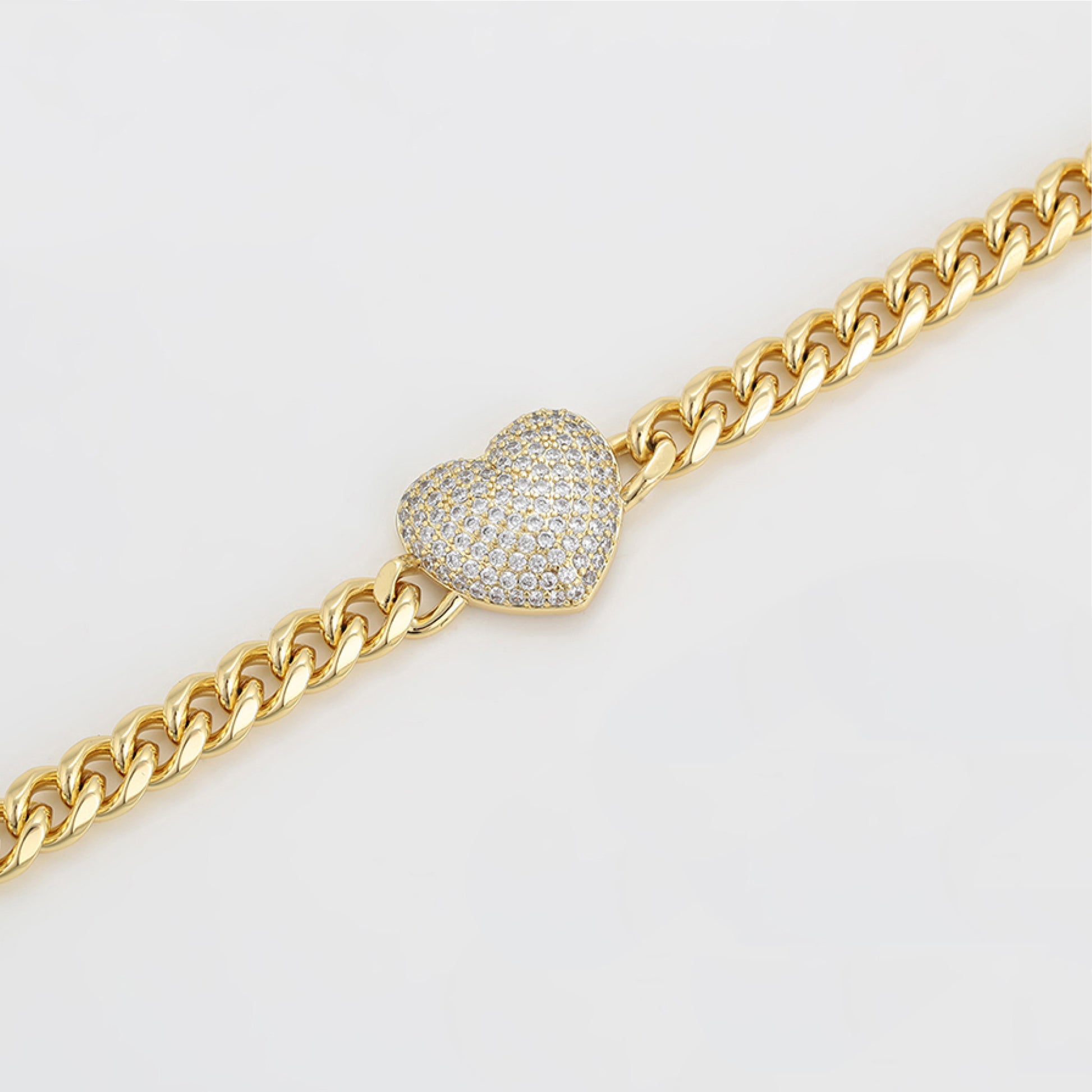 Gold chain bracelet with a heart-shaped diamond clasp on a light gray background