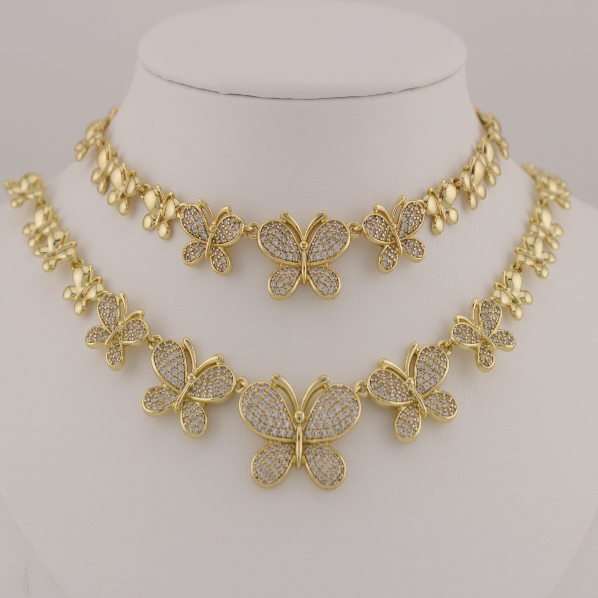 Gold butterfly necklace on a mannequin bust against a neutral background