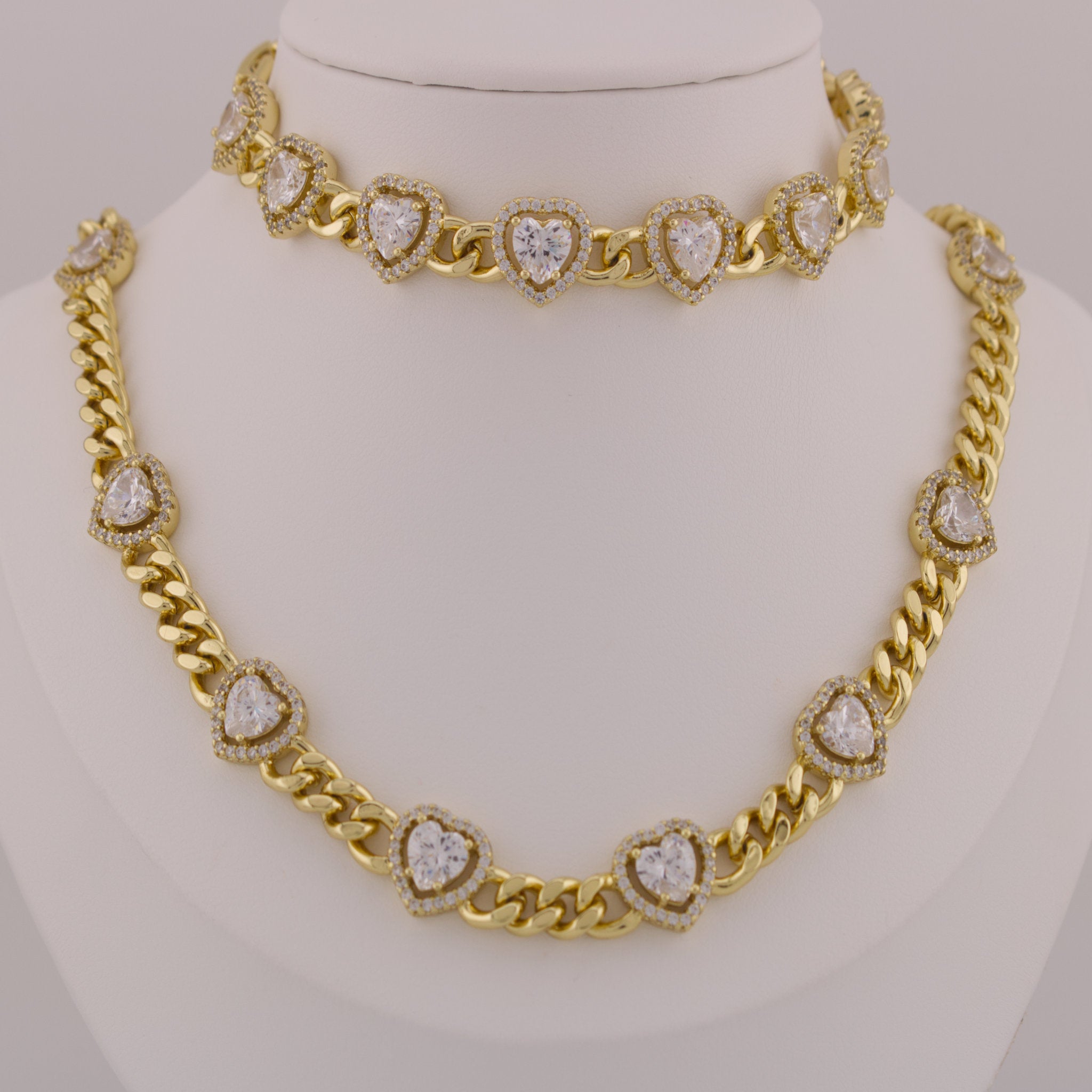 Gold necklace with heart-shaped diamond pendants on a mannequin.