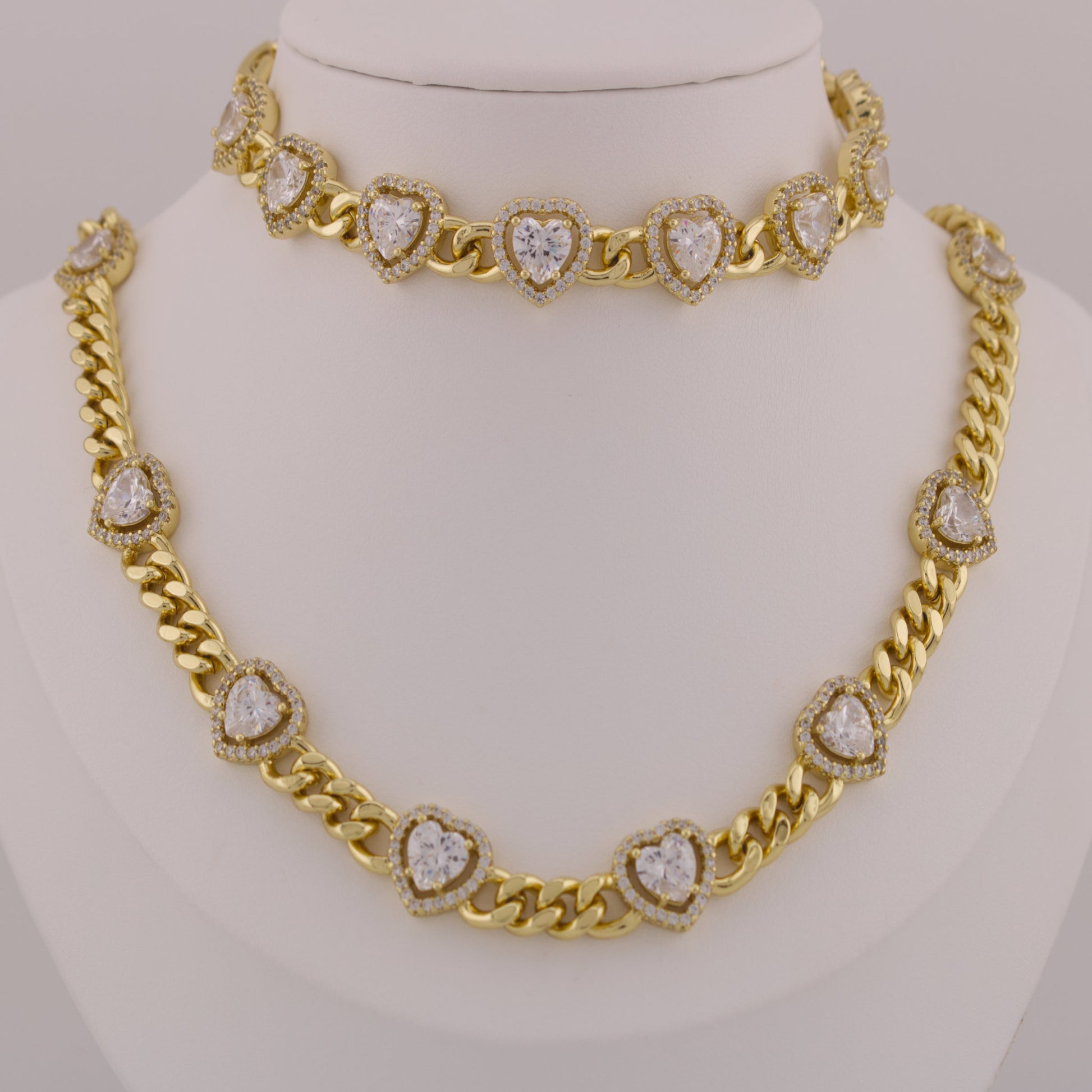 Gold necklace with heart-shaped diamond pendants on a mannequin.