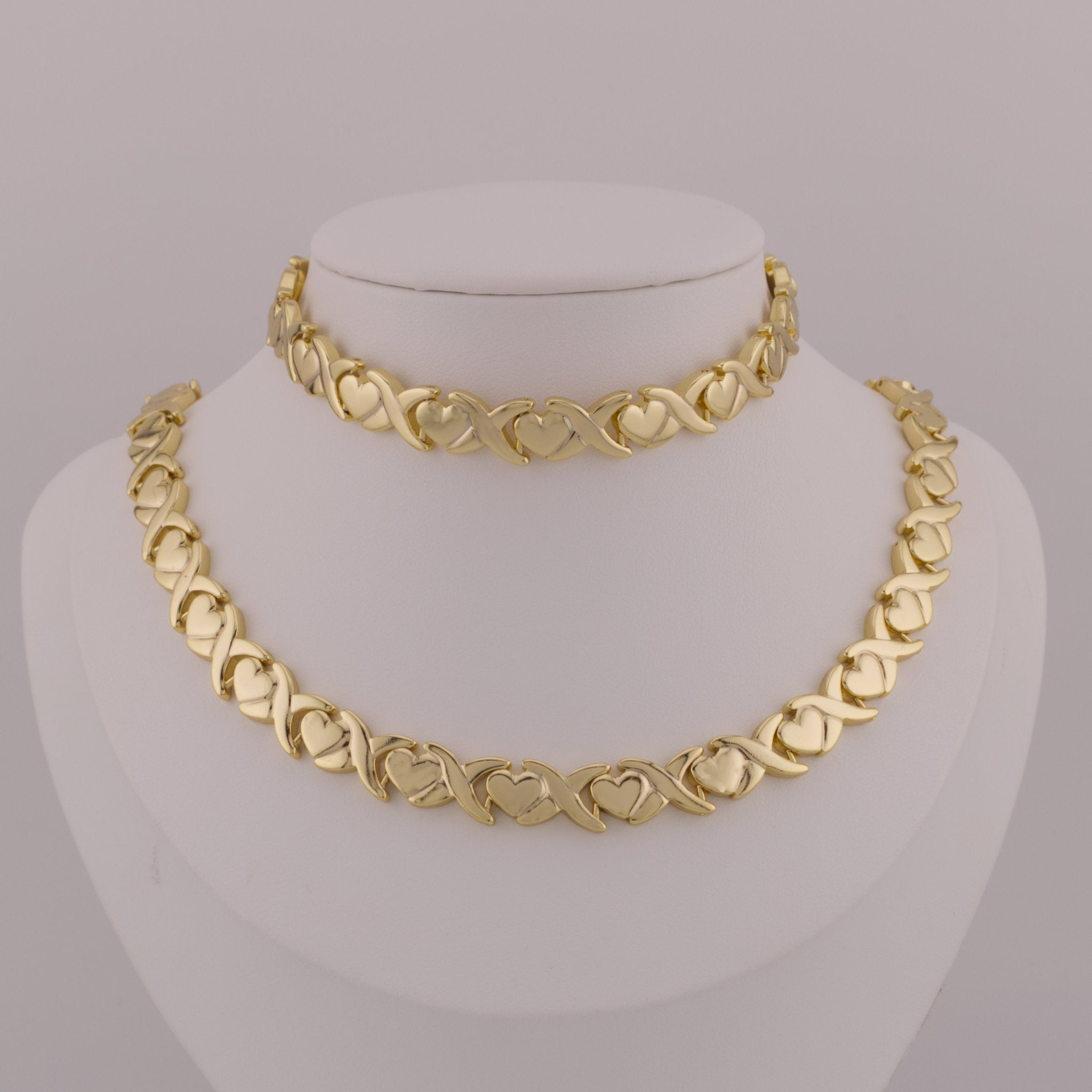 Gold necklace on a mannequin bust against a gray background