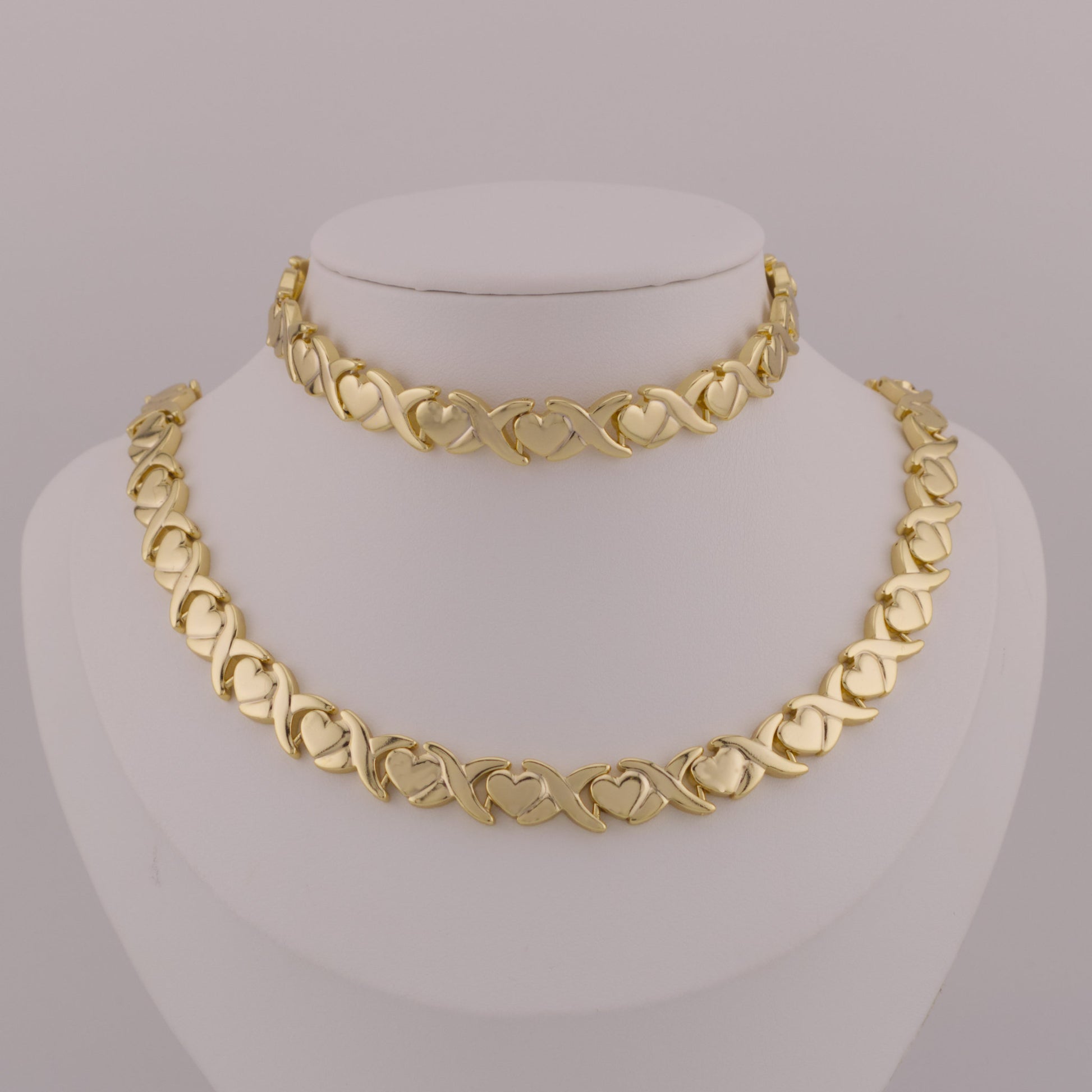 Gold necklace on a mannequin bust against a gray background