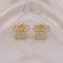 Gold butterfly earrings with clear stones on a beige background