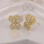 Gold butterfly earrings with gemstones on a soft white background