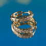 Gold hoop earrings with diamond accents on a blue background