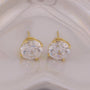 Gold earrings with large clear gemstones on a light background