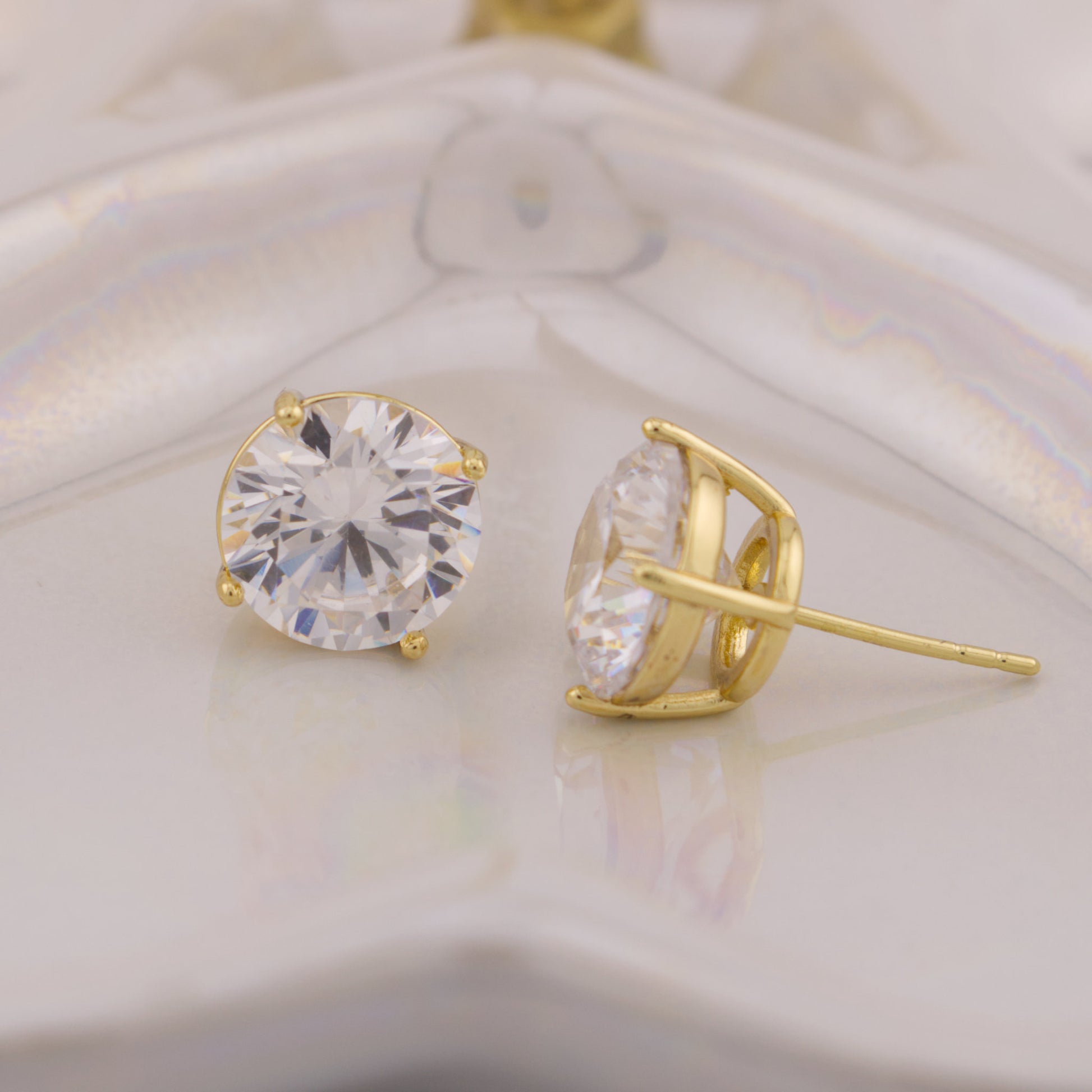 Gold stud earrings with clear gemstones on a white background