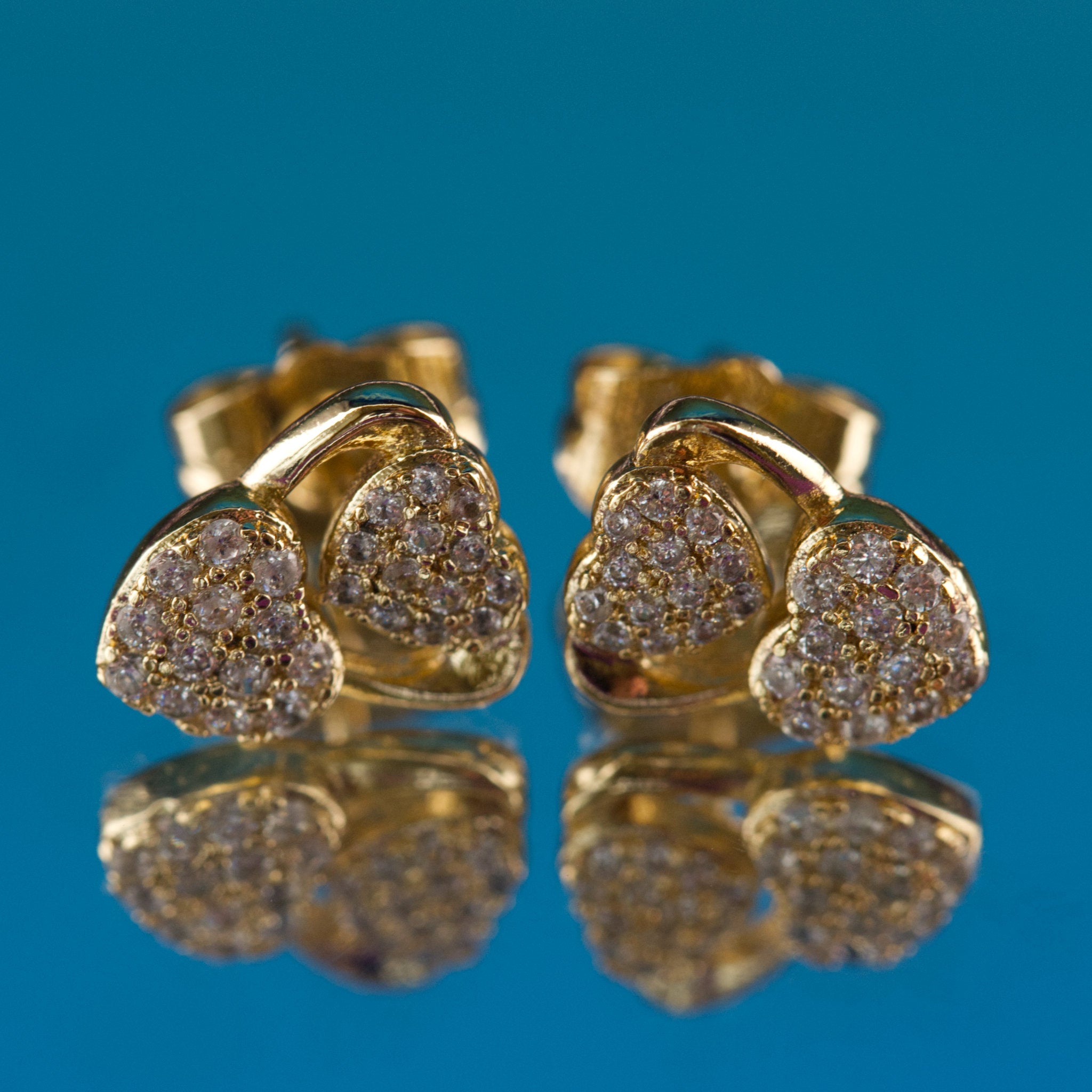 Gold earrings with diamond accents on a blue background