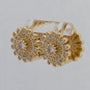 Gold hoop earrings with floral design and clear gemstones on a light gray background