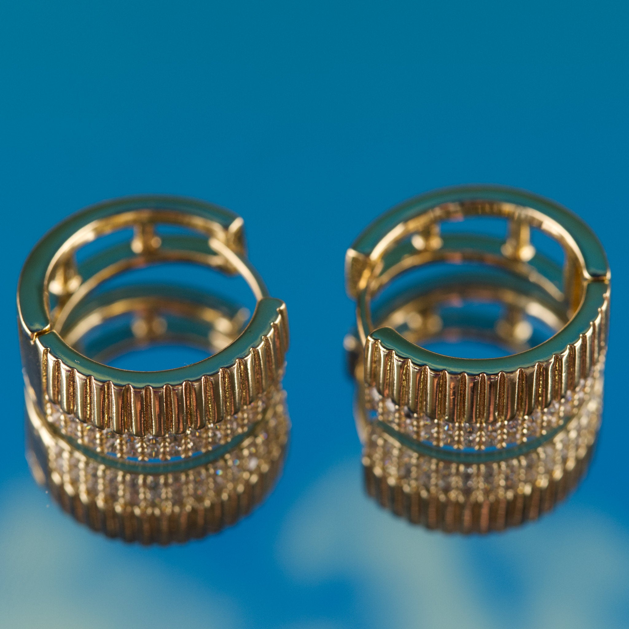 Pair of gold hoop earrings on a blue background