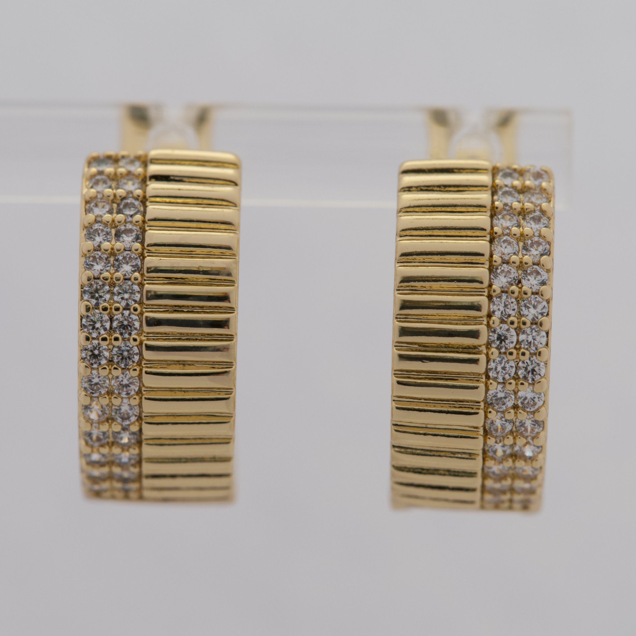 Gold hoop earrings with diamond accents on a light gray background