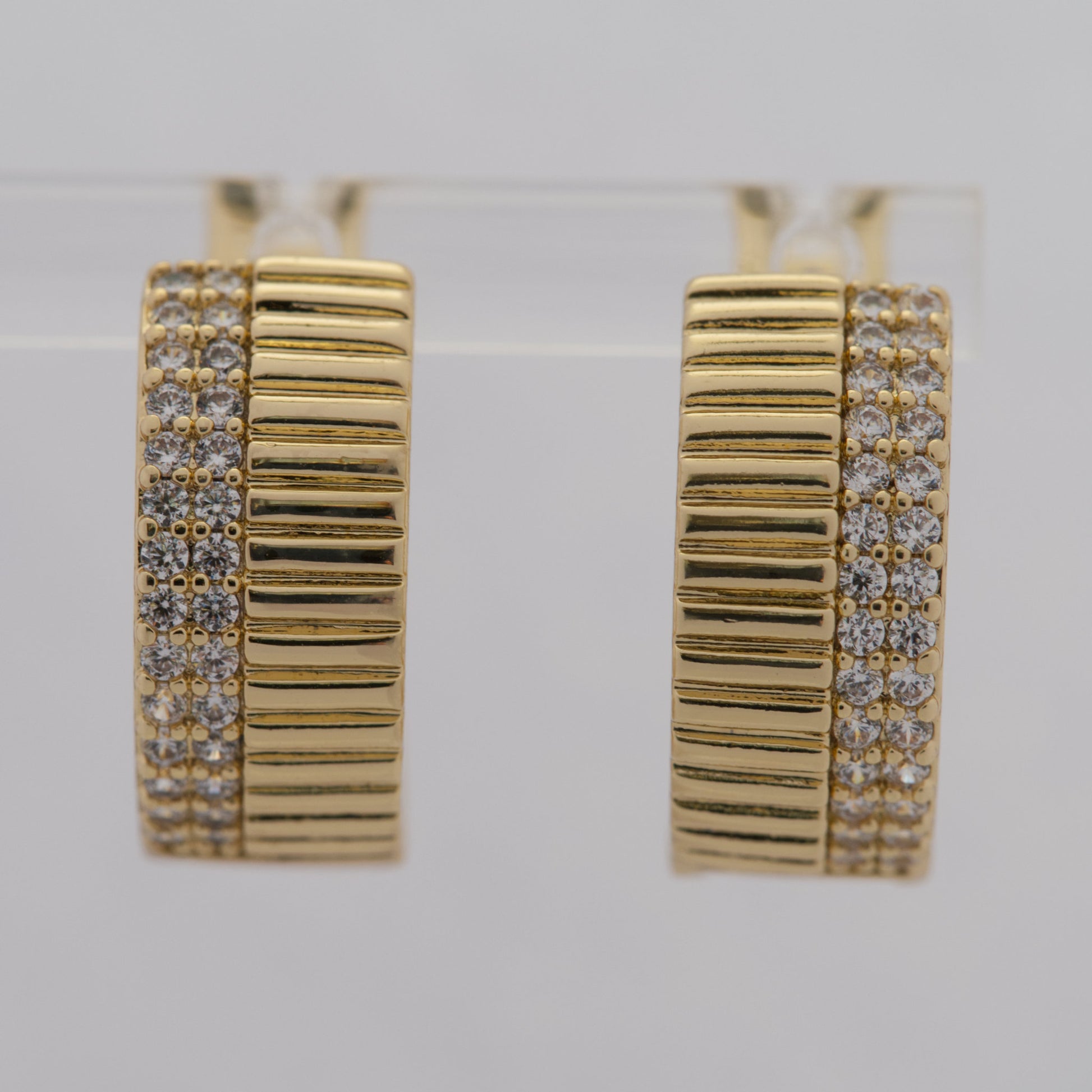 Gold hoop earrings with diamond accents on a light gray background