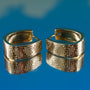 Pair of gold hoop earrings with intricate design on a blue background