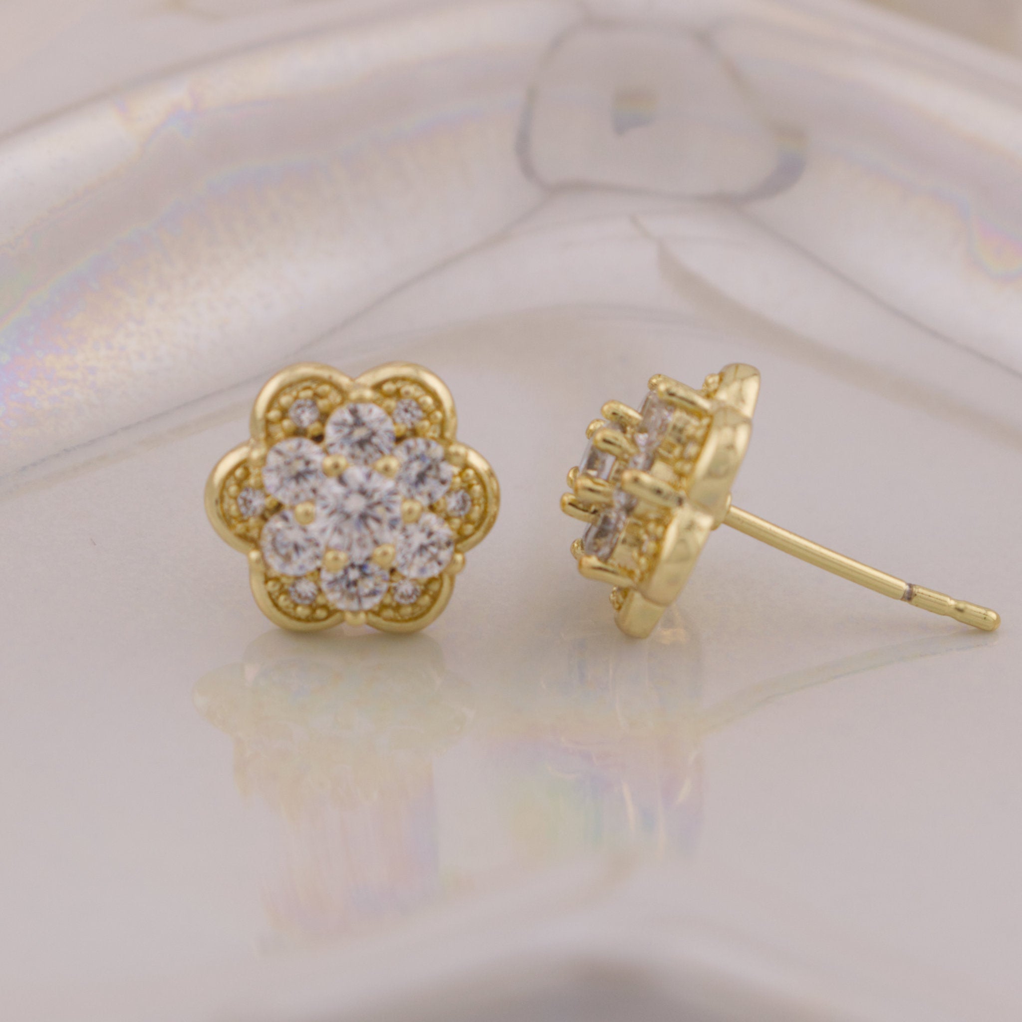 Gold earrings with diamond-like stones on a light background