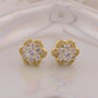 Gold flower-shaped earrings with clear gemstones on a light background