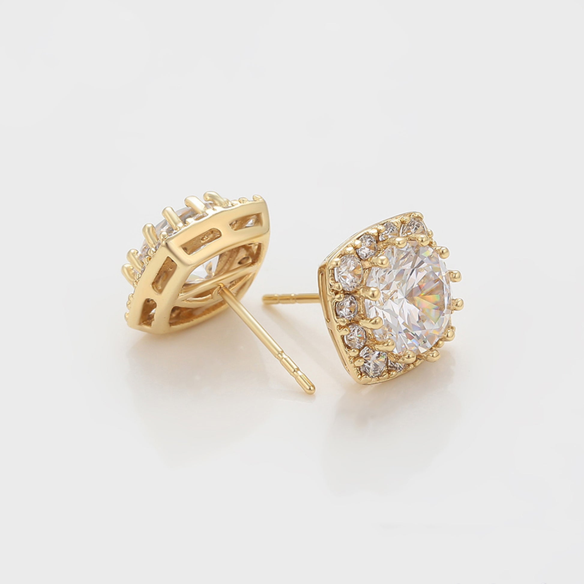 Gold earrings with clear gemstones on a light gray background