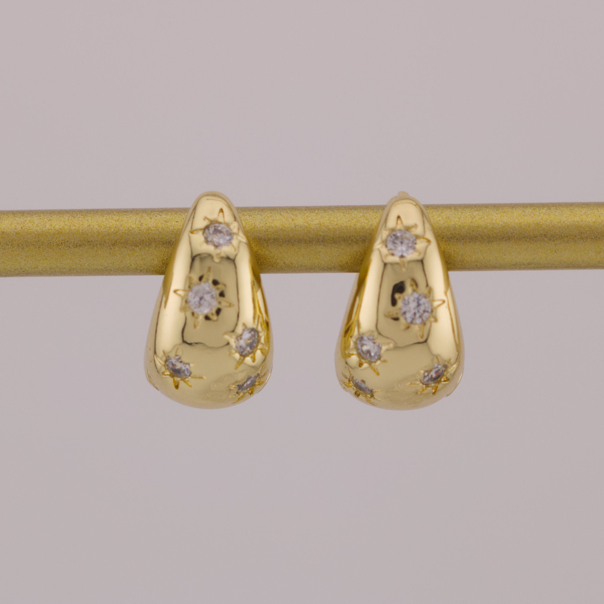 Gold earrings with diamond accents on a gray background
