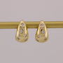 Gold earrings with diamond accents on a gray background