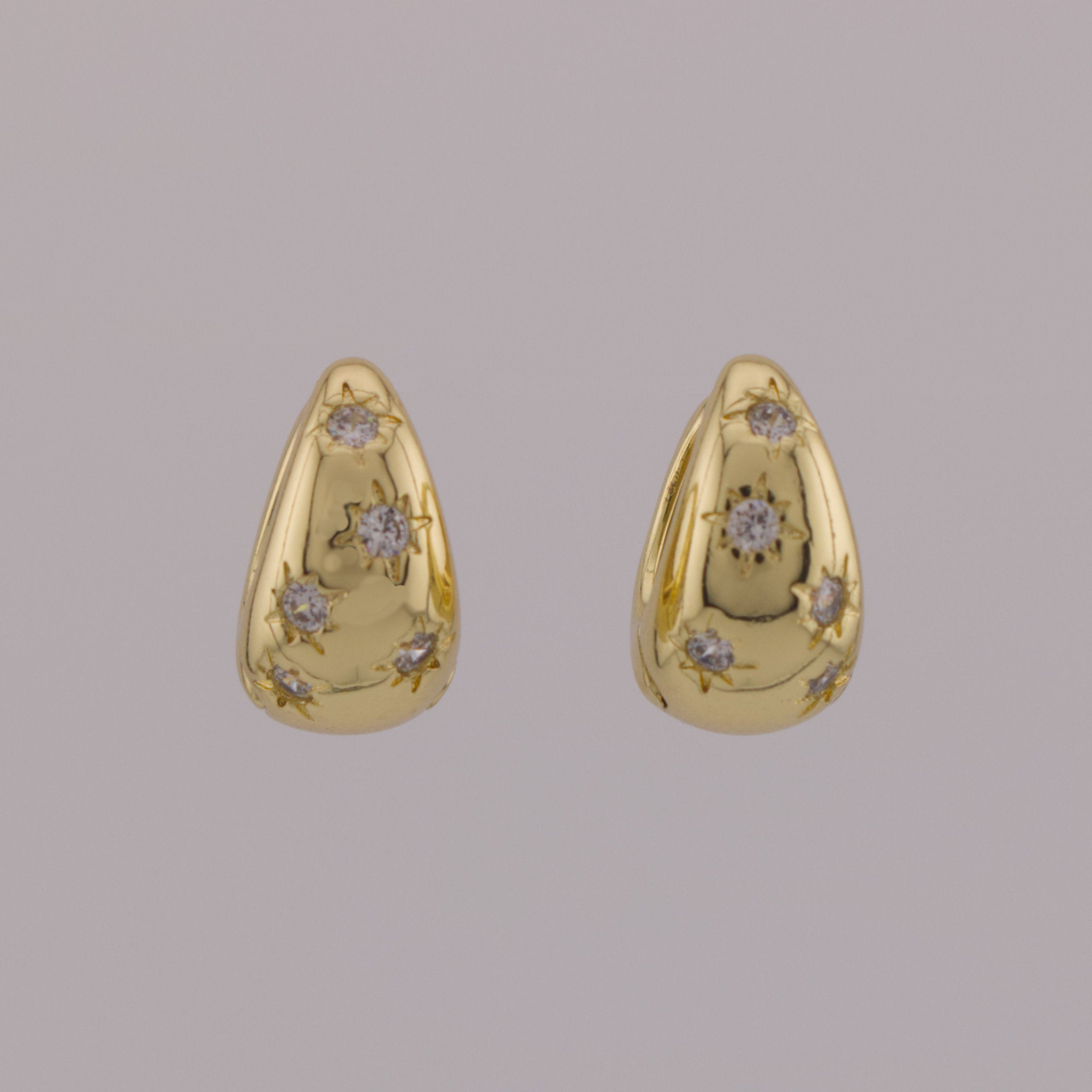 Pair of gold earrings with diamond accents on a gray background