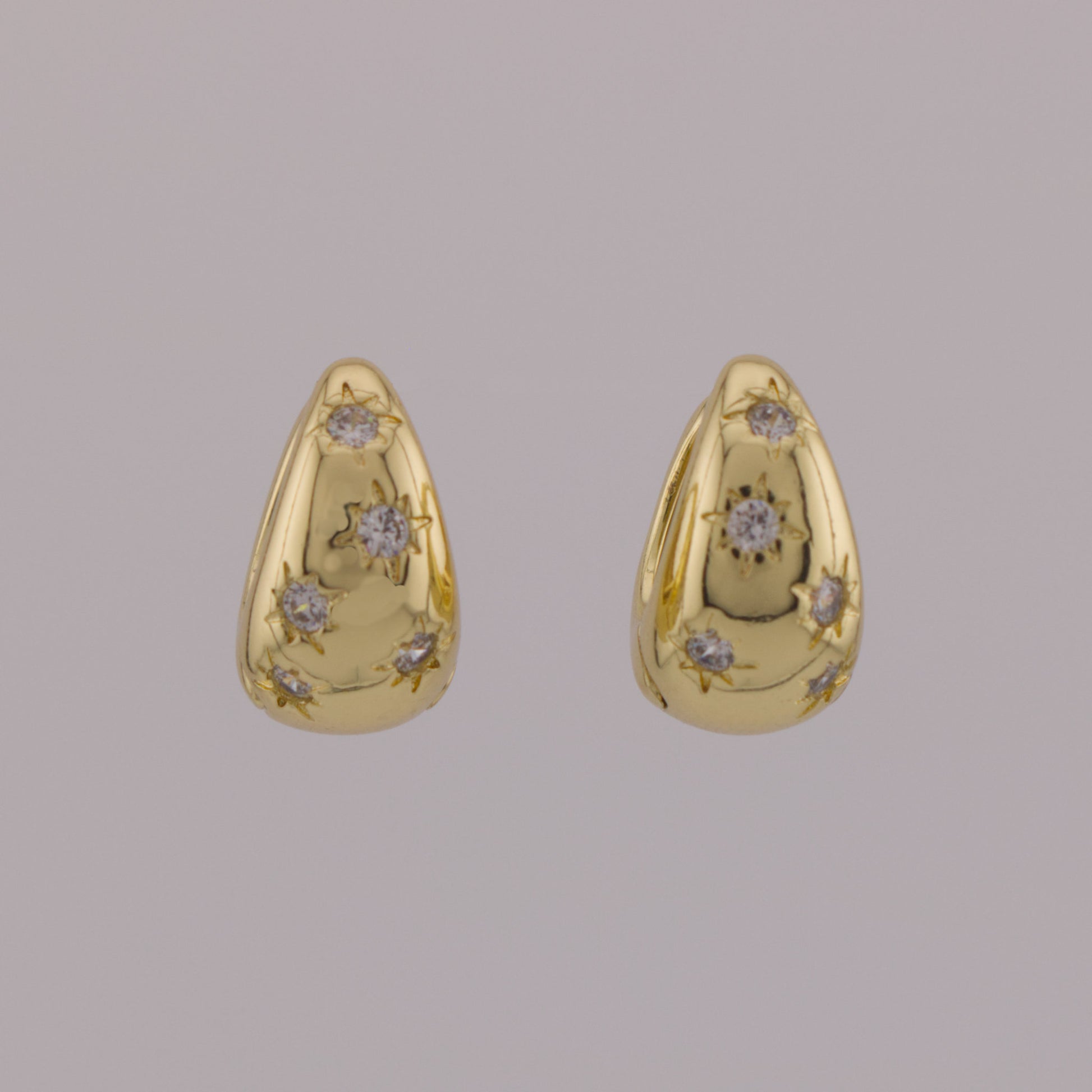 Pair of gold earrings with diamond accents on a gray background