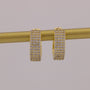 Gold hoop earrings with clear stones on a gold rod against a gray background