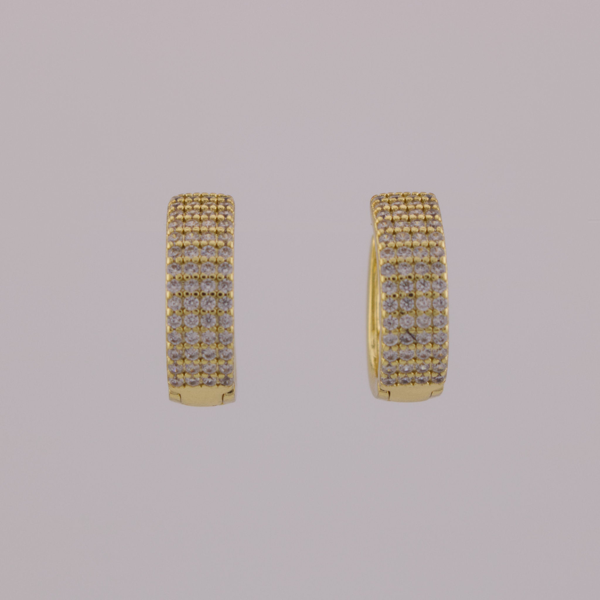 Gold hoop earrings with embedded stones on a gray background