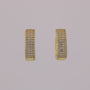 Gold hoop earrings with embedded stones on a gray background