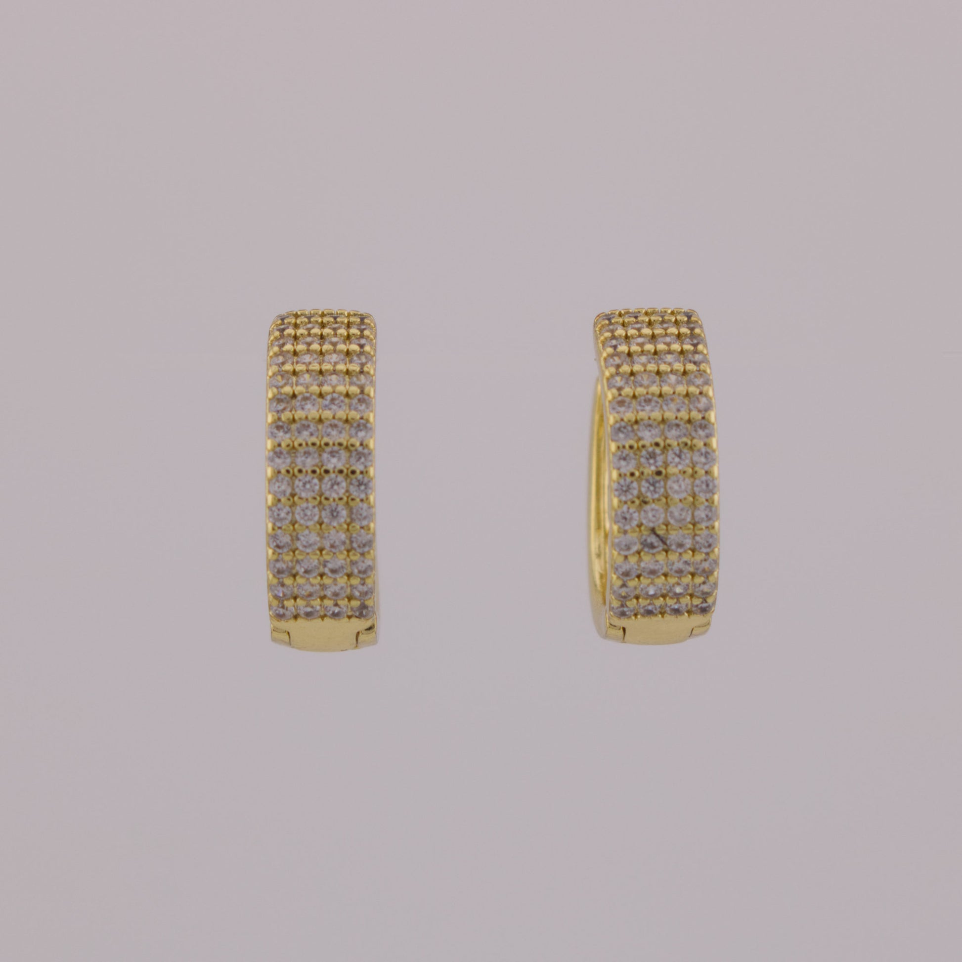 Gold hoop earrings with embedded stones on a gray background