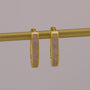 Gold hoop earrings with embedded stones on a gray background