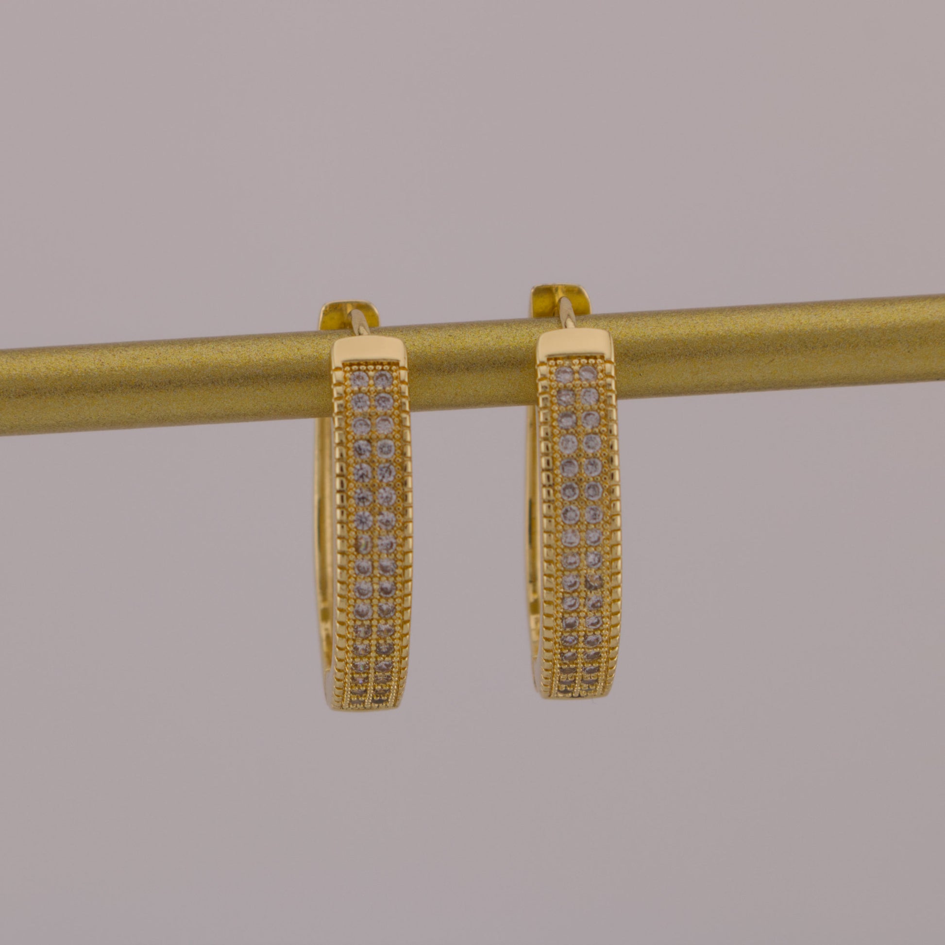Gold hoop earrings with embedded stones on a gray background