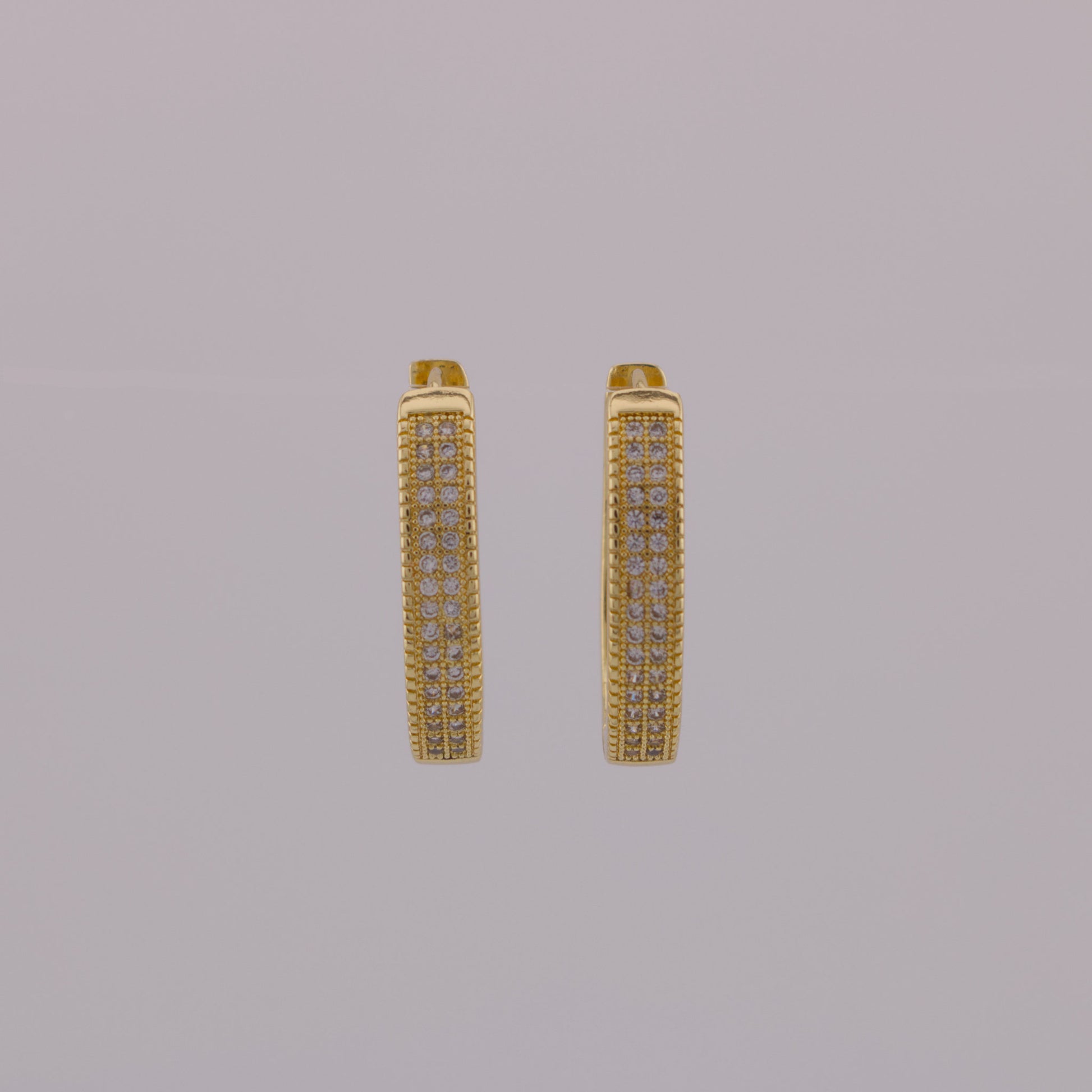 Gold hoop earrings with embedded stones on a gray background