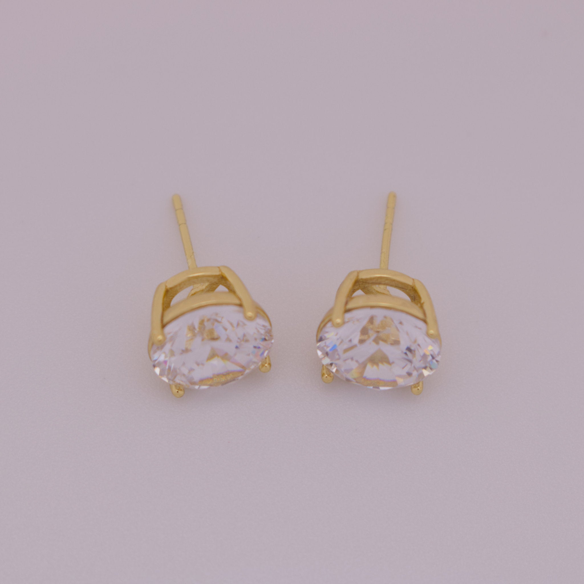 Gold earrings with clear gemstones on a light gray background